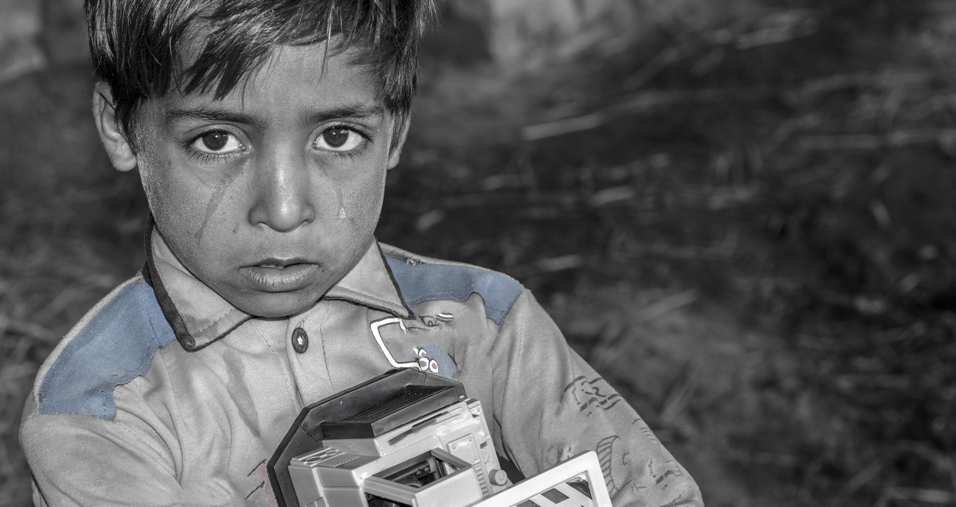 closeup of a poor staring hungry orphan boy in a refugee camp with sad expression on his face and his face and clothes are dirty and his eyes are full of pain